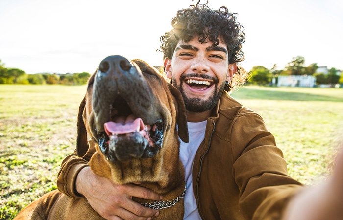 TRUE NORTH FEDERAL CREDIT UNION YOUNG MAN WITH DOG POSING OUTDOORS