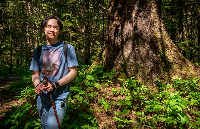 austin posing in front of lage tree in juneau alaska