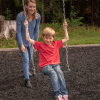 amy pushing son on swing in a playground