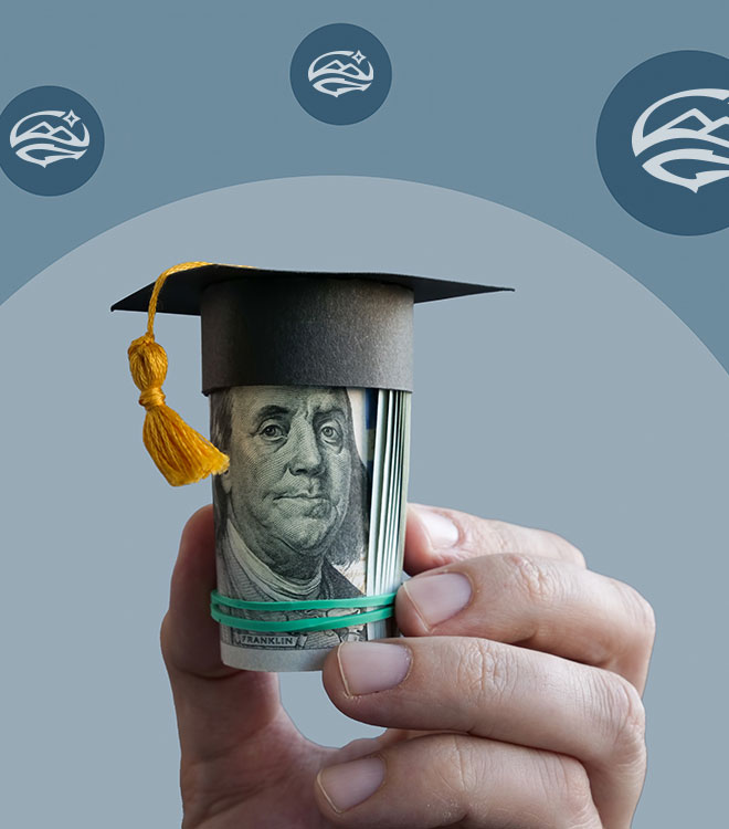 hand holding up a roll of hundred dollar bills with ben franklin facing forward Roll of money has a graduation cap on top of it